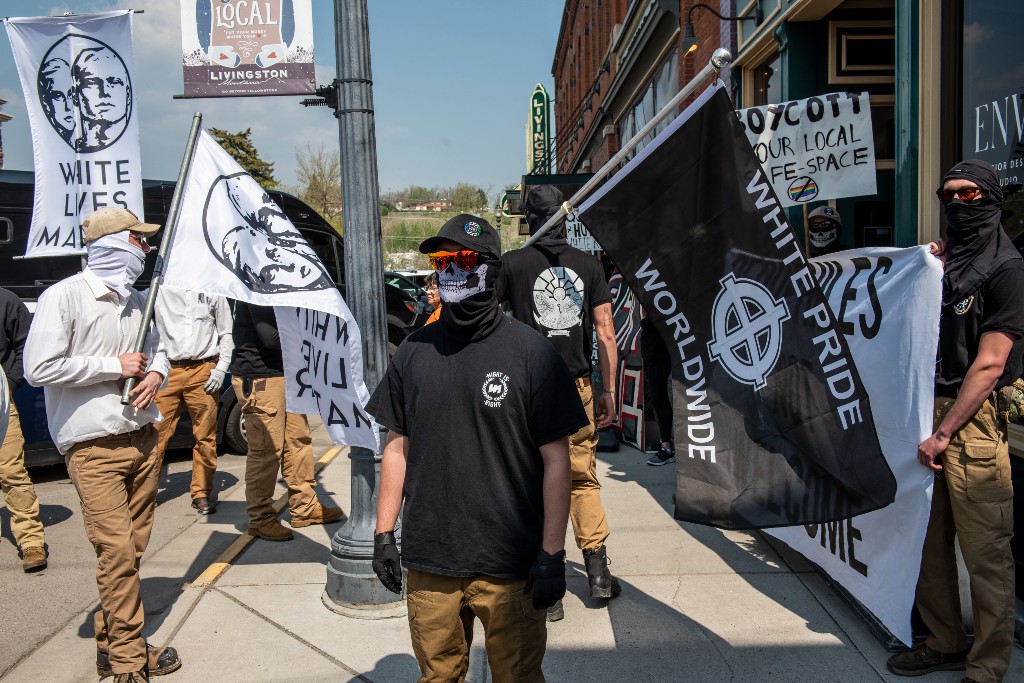 Right-wing white nationalists hold flags with signs like "white pride worldwide."