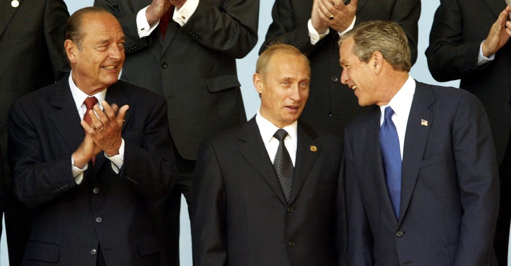 French President Jacques Chirac at the left of the image is applauding as he smiles at Russian President Vladimir Putin in the center of the image and US President George W. Bush, who is laughing as Putin seems to smile and gape at the display.