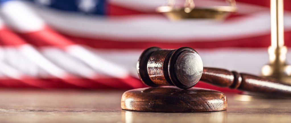 Gavel and scales with a US flag in the background as symbols of a jurisdiction.