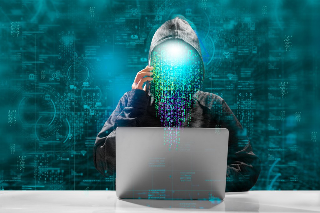 A faceless hacker running malware on a laptop