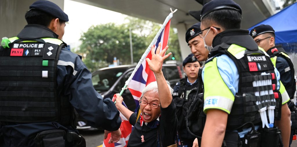 A pro-democracy protester engages with police while holding a flag in Hong Kong.