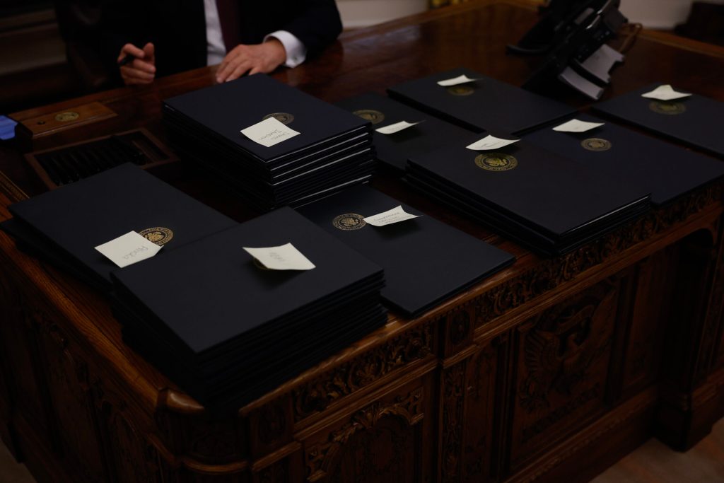 Binders of executive orders stacked on a desk.