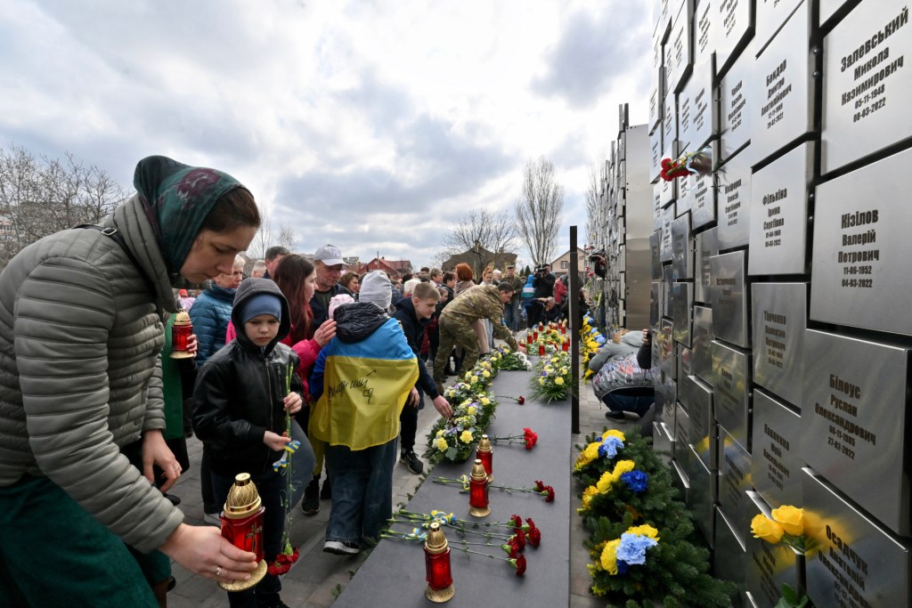 People lay flowers and set candles to memorial