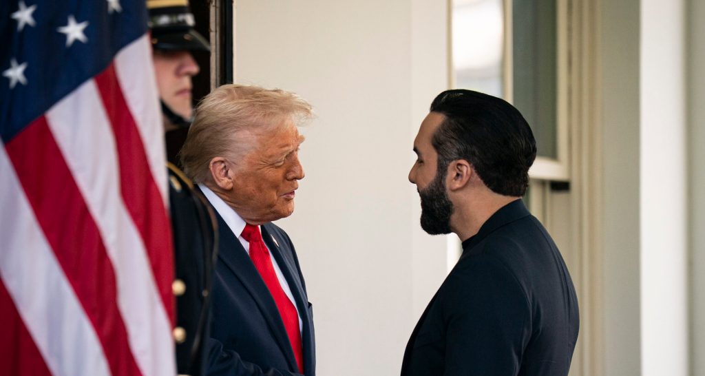 U.S. President Donal Trump shakes hands with El Salvador Presidnet Nayib Bukele next to an American flag.