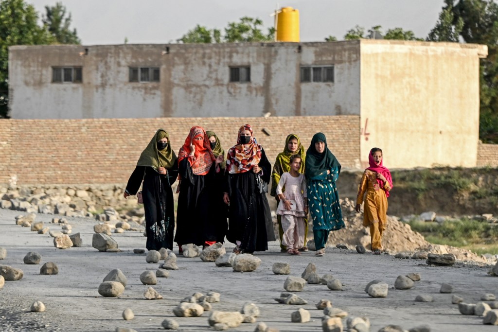 Afghan women walk along a stone-laden street on the outskirts of Kabul on July 22, 2025. (Photo by WAKIL KOHSAR/AFP via Getty Images)