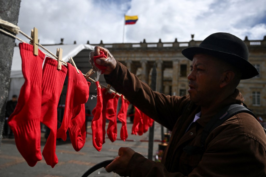 A man hangs wet socks in the colors of the Colombian flag as a symbolic act to commemorate National Human Rights Day in Bogotá on September 9, 2025. (Photo by RAUL ARBOLEDA/AFP via Getty Images)