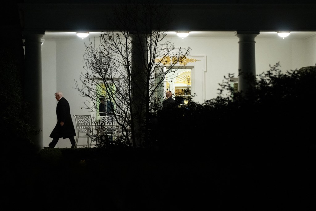 Silhouette of President Donald Trump outside the White House in the evening.