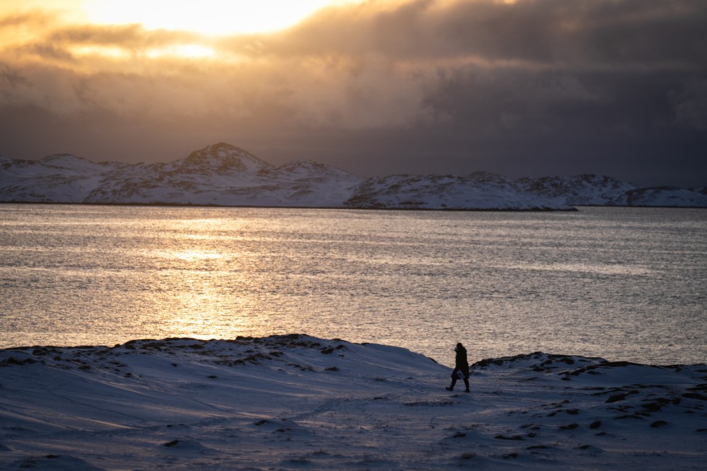 A person enjoys an afternoon walk near the sea on January 15, 2026 in Nuuk, Greenland. (Photo by Alessandro RAMPAZZO / AFP via Getty Images)