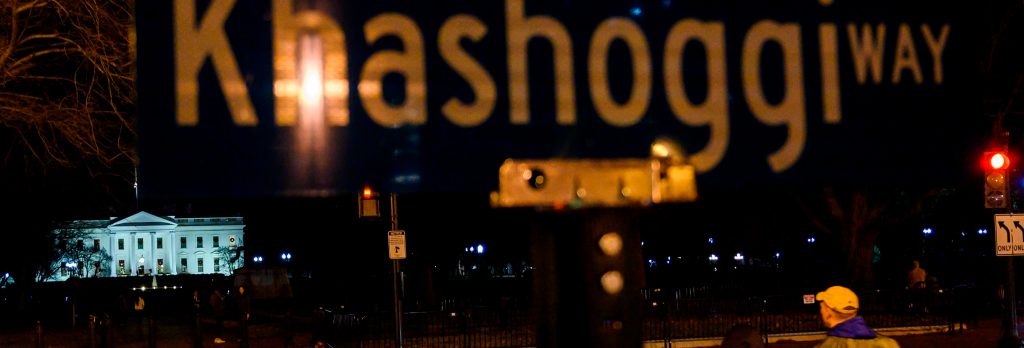 People cross the street near a protest sign reading "Khashoggi way" across the street from the White House in Washington, DC, on December 23, 2018.