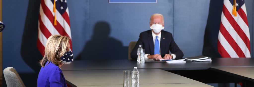 Speaker of the House Nancy Pelosi (D-CA) sits with U.S. President-elect Joe Biden during a meeting that included Vice President-elect Kamala Harris and Senate Democratic Leader Chuck Schumer (D-NY) (not shown) at the Queen Theater on November 20, 2020 in Wilmington, Delaware. They sit at a large horse-shoe or square table allowing ample room for social distancing. An American flag stands behind the table near President-elect Biden.